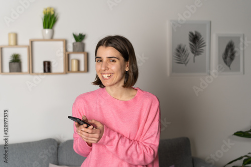 girl with a smartphone in hand at home. look at camera, smile