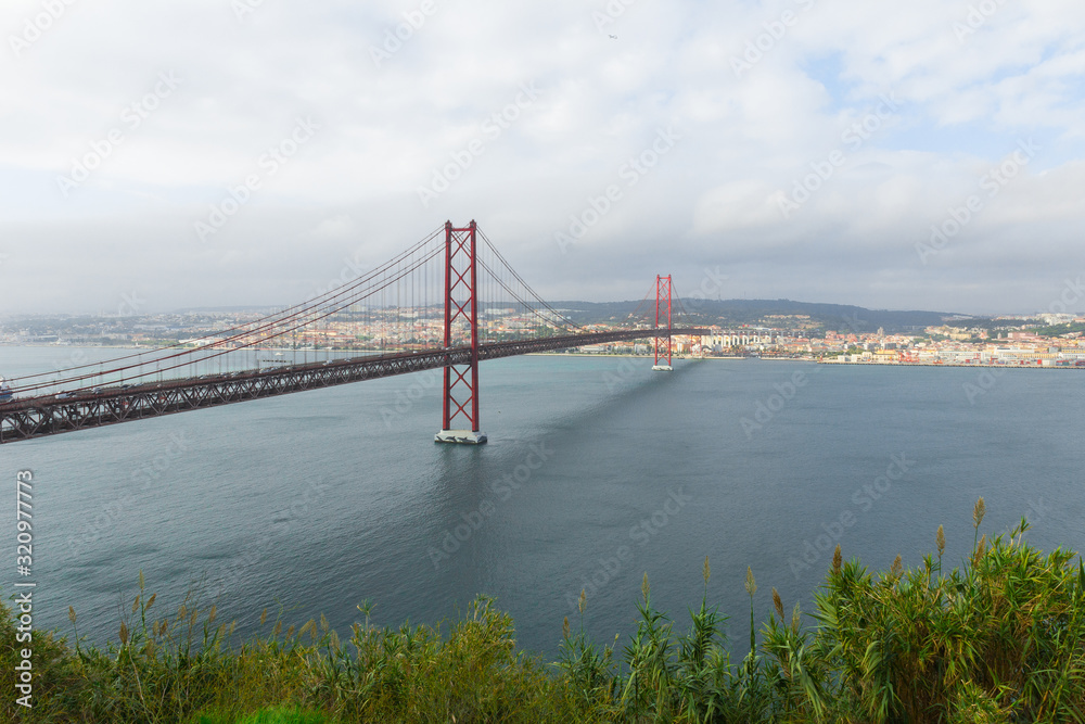 25 de abril bridge (25th of April Bridge), Almada, Portugal. Beautiful red suspension bridge connected to the portuguese capital of Lisbon. Often compared to the Golden Gate Bridge in San Francisco.