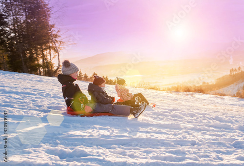 Children ride from a snow slide, have fun, play. Happy winter ho