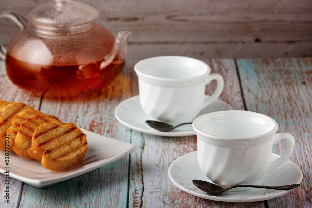 Freshly made tea in a teapot with cookies and jam on the table