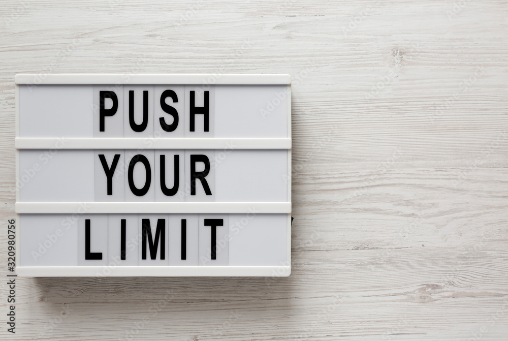 'Push your limit' words on a lightbox on a white wooden surface, top view. Overhead, from above, flat lay. Space for text. 'Push your limit' words on a lightbox on a white wooden surface, top view. Overhead, from above, flat lay. Space for text.