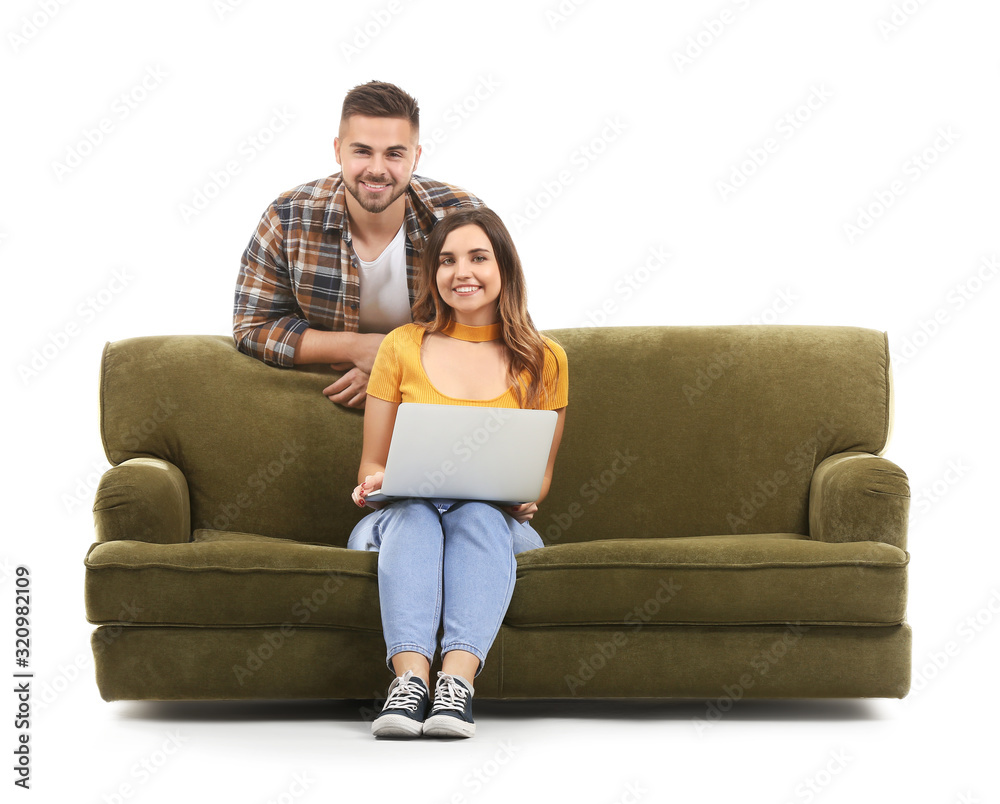 Young woman with laptop sitting on sofa and her husband against white background Young woman with laptop sitting on sofa and her husband against white background
