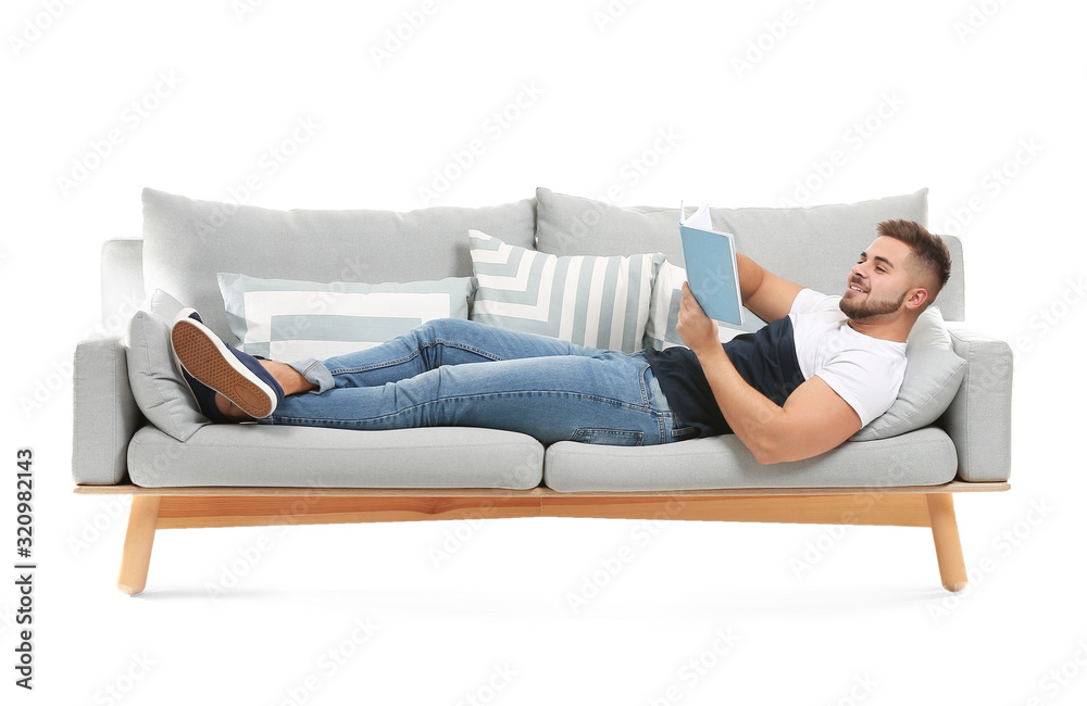 Young man with book lying on sofa against white background