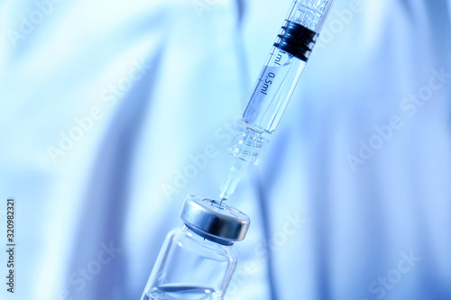 Syringe with filler for cosmetology and ampule on color background, closeup