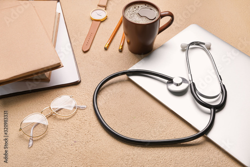 Stethoscope with laptop and stationery on color background