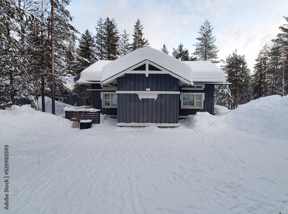 Wooden, snow-covered gray house in a forest in Lapland. Comfort, silence, snowy winter, country life