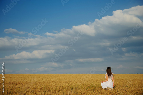 back view of a woman in white dress in wheat field