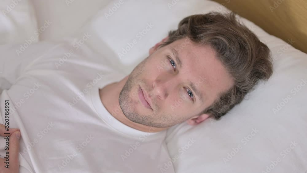 Portrait of Young Man Looking at Camera from Bed Portrait of Young Man Looking at Camera from Bed