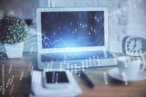 Stock market graph on background with desk and personal computer. Multi exposure. Concept of financial analysis.