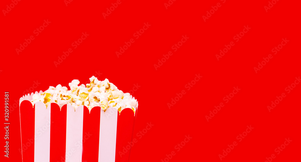 Large square striped box with salty popcorn on red background. Cinema concept,with clipping path