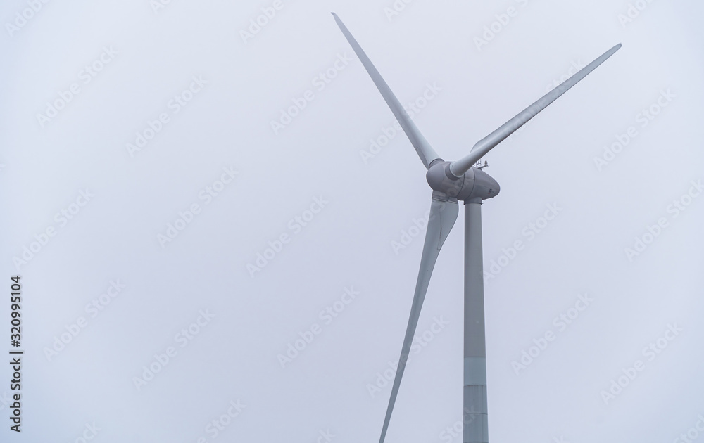 Single wind turbine isolated against clear white sky. Single wind turbine isolated against clear white sky.