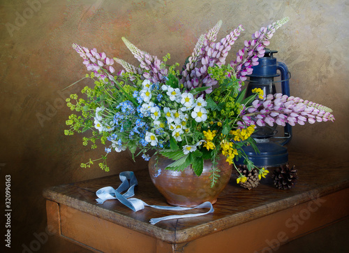 Still life with a bouquet of wild flowers in a clay vase on the table