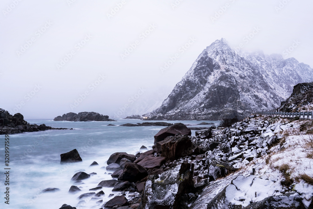 Winter picture of Lofoten islands with seashore cliffs and mountain on horizon.