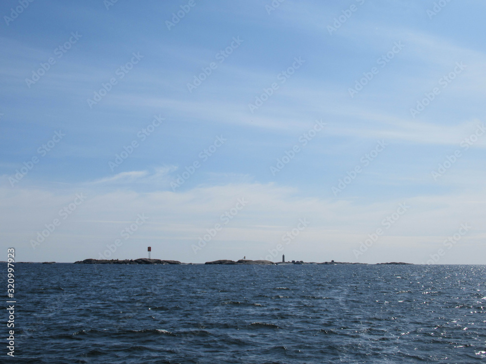 Seascape with small islands and a lighthouse on a sunny day.