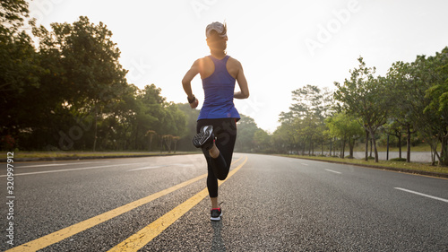 Young fitness asian woman runner running on city road in the sunirse