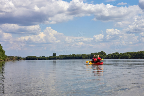 Couple man and woman kayaking on the Danube river at summer day. Together enjoying adventurous experience with kayak. © watcherfox