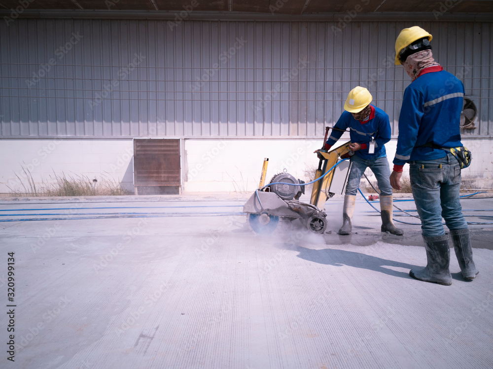 Saw cut control joints in concrete, worker is cutting longitudinal