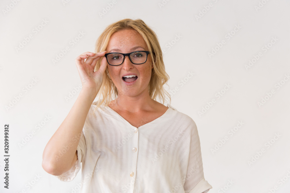 Surprised blonde woman in spectacles. Portrait of emotional young woman adjusting eyeglasses and looking at camera. Surprise concept Surprised blonde woman in spectacles. Portrait of emotional young woman adjusting eyeglasses and looking at camera. Surprise concept
