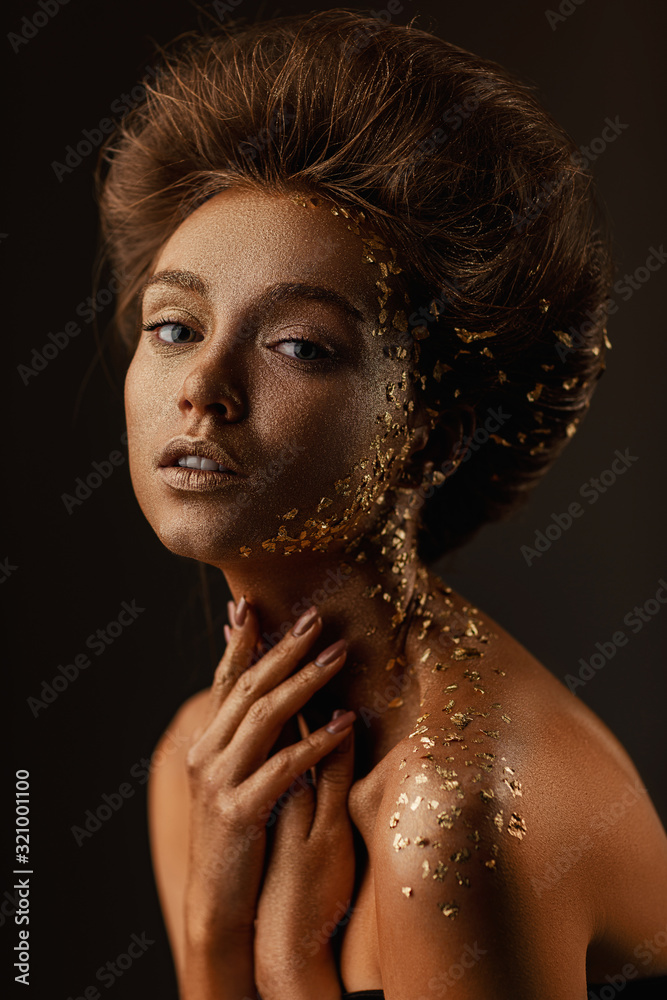 Fototapeta Moda sztuka portret model dziewczyna z wakacje złoty błyszczący profesjonalny makijaż. beaty kobieta ze złotym metalicznym ciałem i włosami na ciemnym tle. Złota świecąca skóra.