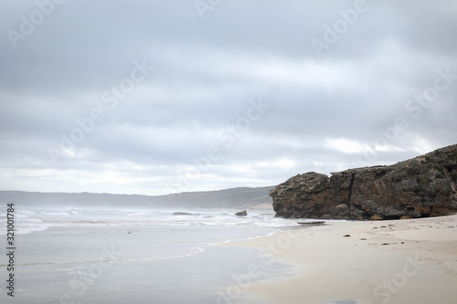 Beach scene with wind turbines on a cliff on an overcast day along the Great Ocean Road at Portland, Victoria Australia