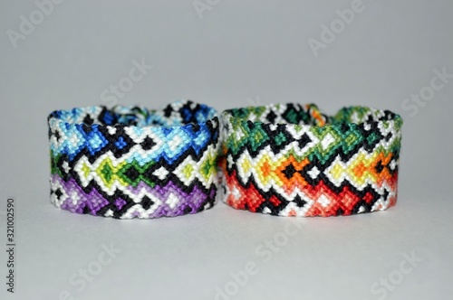 Two multi-colored friendship bracelets handmade of embroidery bright floss isolated on white background