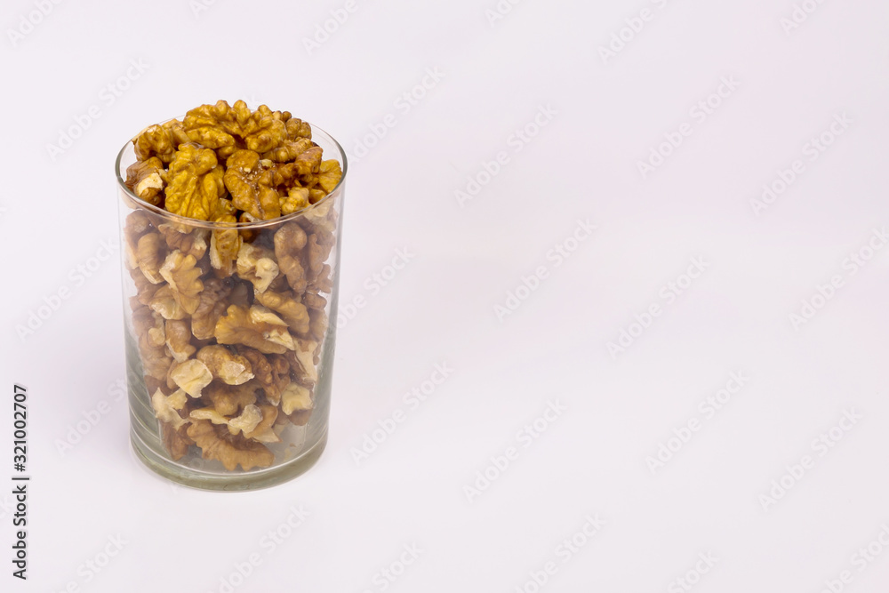 A glass of walnuts. Peeled nuts on a white background. A glass of walnuts. Peeled nuts on a white background.