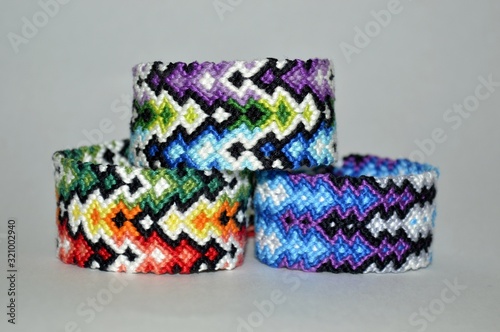 Three colorful and multi-colored friendship bracelets handmade of embroidery bright floss and thread with knots isolated on white background