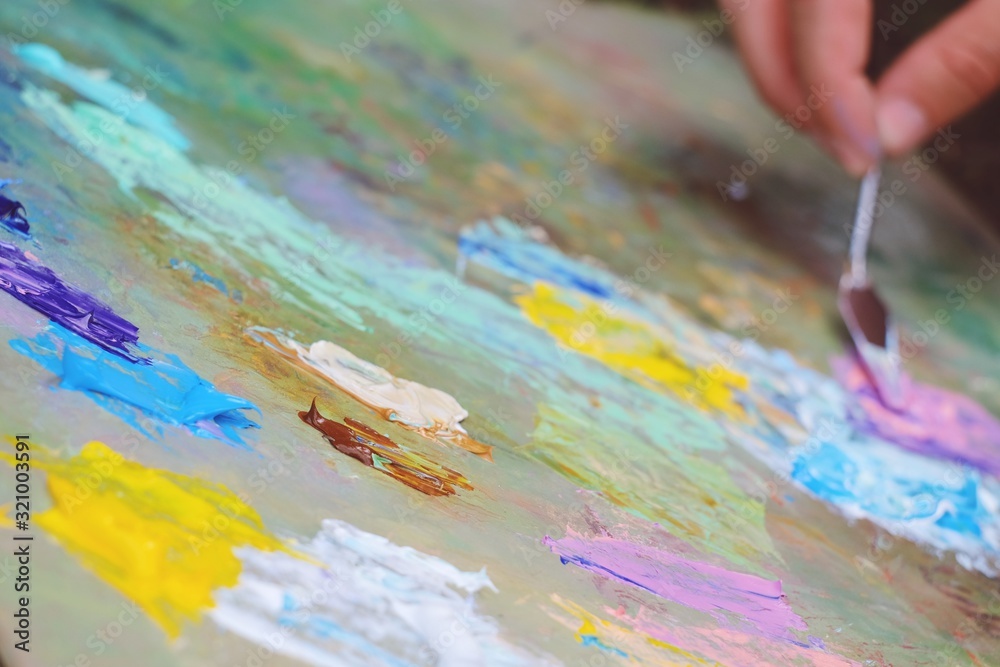 Close up mixing oil paints on the palette. Colorful workplace of the artist with oil paints. Oil paints texture background. Close up mixing oil paints on the palette. Colorful workplace of the artist with oil paints. Oil paints texture background.