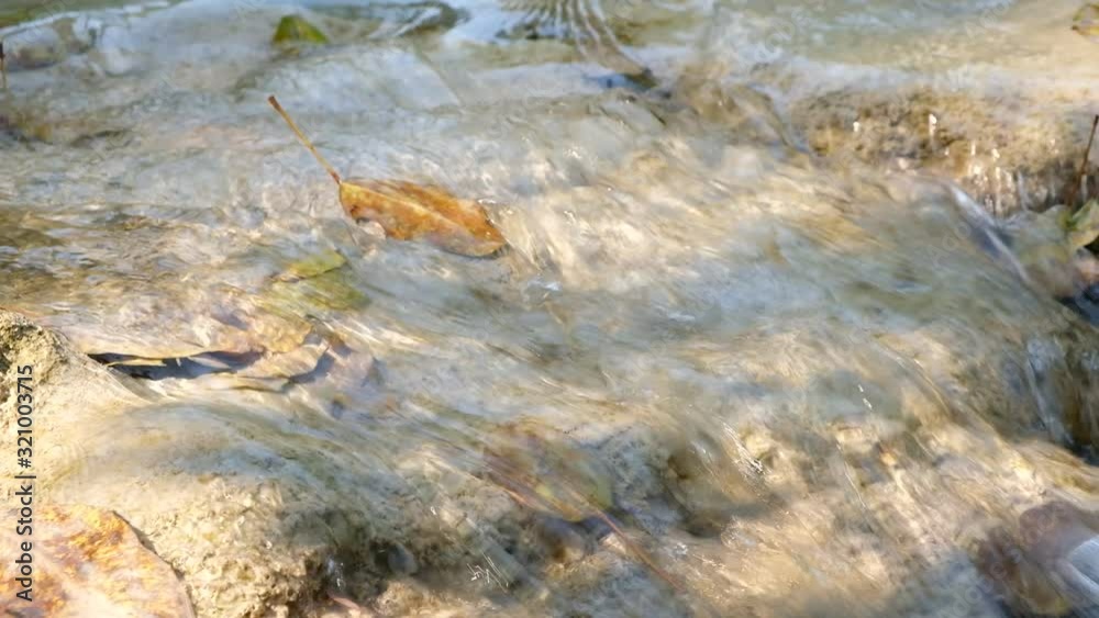 Closeup. The stream flows water with brown rocks. Closeup. The stream flows water with brown rocks.