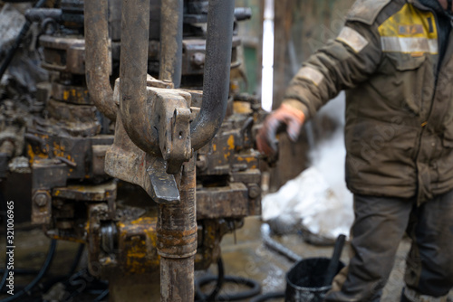 Fototapeta Naklejka Na Ścianę i Meble -  Offshore oil rig worker prepare tool and equipment for perforation oil and gas well at wellhead platform. Making up a drill pipe connection. A view for drill pipe connection from between the stands.