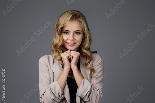 Portrait of young happy woman dreaming about something on gray background. girl made a wish