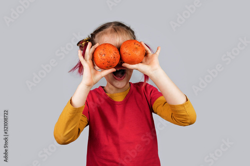 Freakish kid holds misshapen wrong color fruits and vegetables, waste food concept