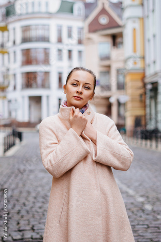 Outdoor portrait of young beautiful caucasian woman in pink coat  © kaloriya