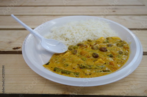 Photography Indian curry and rice portion on a plastic plate with a plastic fork