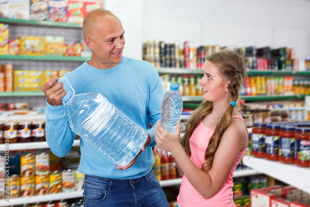 family of positive father and tween daughter buying still water in supermarket