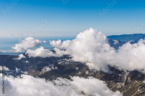 Two small silhouettes of parachutists seen far away in distance. People flying with parachutes in amazing scenic mounts landscape.