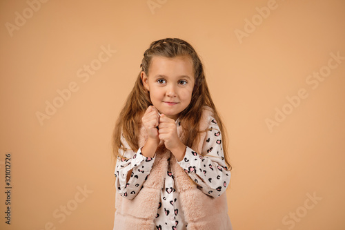 Cute shy little child girl on beige background. Human emotions