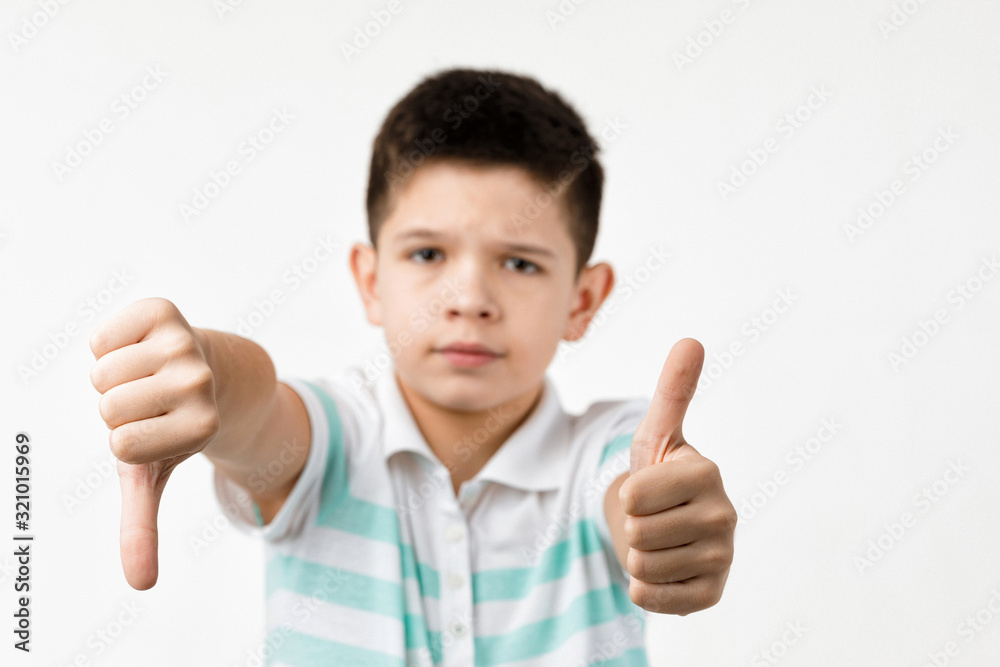 Cute little child boy showing the thumbs down and thumbs up gesture on white background. choice Cute little child boy showing the thumbs down and thumbs up gesture on white background. choice