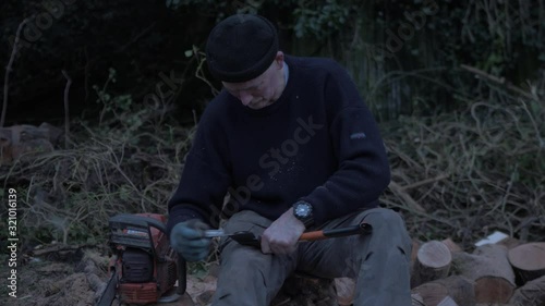 Man sharpening axe within nature photo