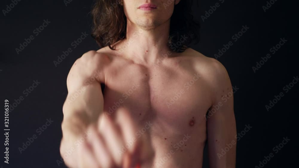 A strong shirtless white man training his shoulder muscles with a resistance band workout in the gym SLOW MOTION. A strong shirtless white man training his shoulder muscles with a resistance band workout in the gym SLOW MOTION.
