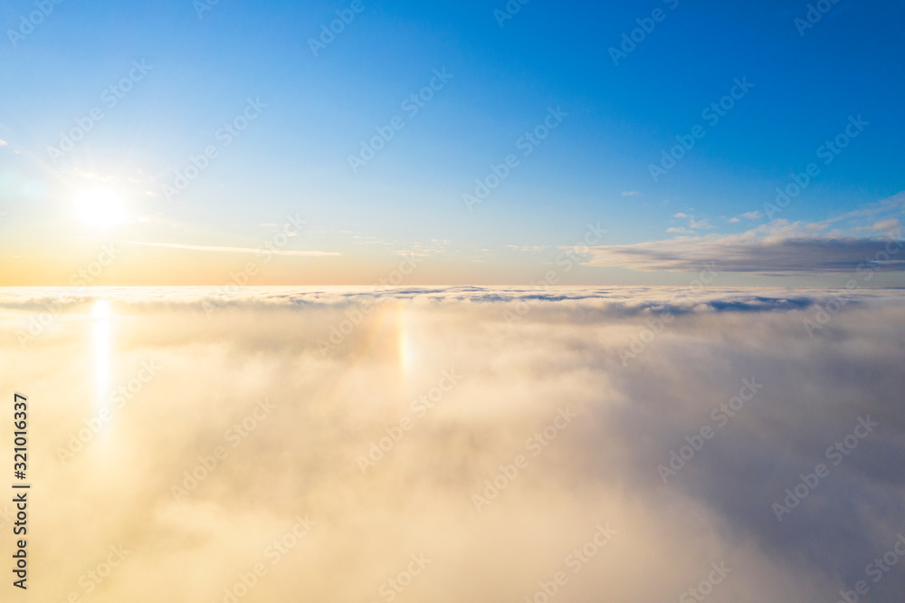 Aerial view White clouds in blue sky with solar halo. Top view. View from drone. Aerial bird's eye view. Aerial top view cloudscape. Texture of clouds. View from above. Sunrise or sunset over clouds