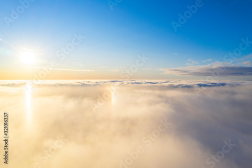 Aerial view White clouds in blue sky with solar halo. Top view. View from drone. Aerial bird s eye view. Aerial top view cloudscape. Texture of clouds. View from above. Sunrise or sunset over clouds