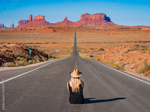 Young blonde girl sits in the center of Forrest Gump Point Road to Monument Valley, region of Colorado Plateau buttes Arizona Utah border photo