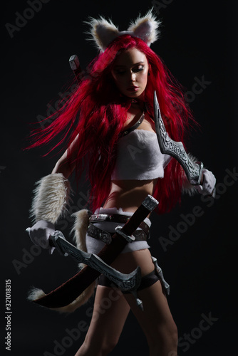 Sexy redhead woman in cosplay costume of warrior cat with swords posing on dark background © FlexDreams