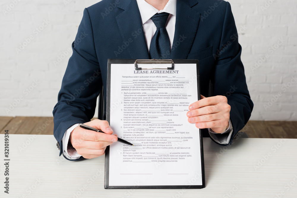 cropped view of realtor holding clipboard with lease agreement lettering on document cropped view of realtor holding clipboard with lease agreement lettering on document