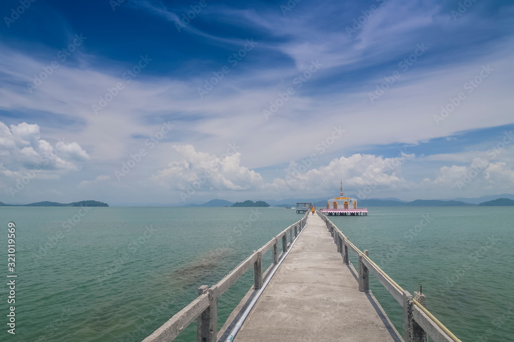 view of patch way with buddhist temple and blue-green sea with cloudy sky background, Wat KohPhayam, Ko Phayam (Ko Payam) island, Ranong, Thailand.