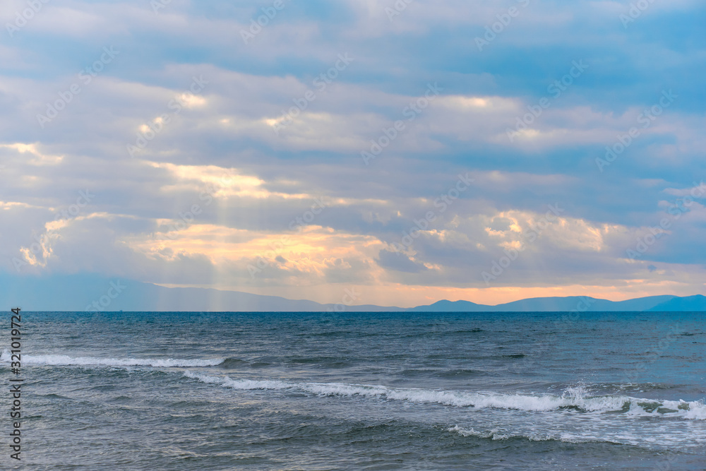 Obraz premium Sunlight beams through the clouds on the beach in a winter day