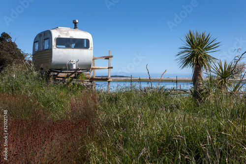 Road to Jackson bay. Westcoast New Zealand. Okuru river. Caravan on poles. Fishing shed.