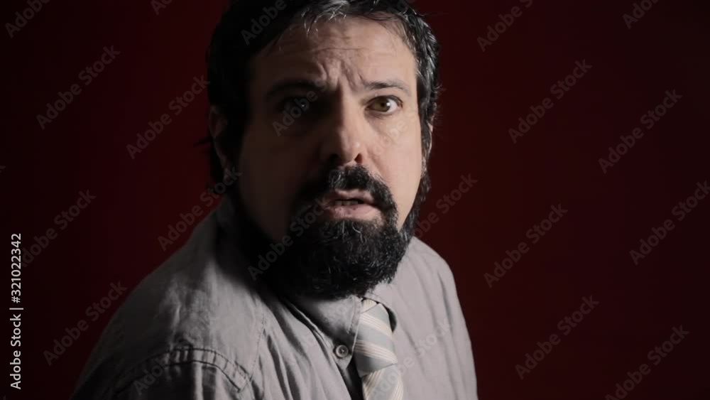 A stuck man's expression. Medium close-up shot of the face over a red background. Part of a series of depictions of feelings and emotions with professional actors. A stuck man's expression. Medium close-up shot of the face over a red background. Part of a series of depictions of feelings and emotions with professional actors.