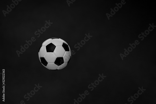 A black-and-white soccer ball flies in the air, isolated on a dark background. The concept of object levitation. Minimalistic black color. Levitating objects. Macro mode.